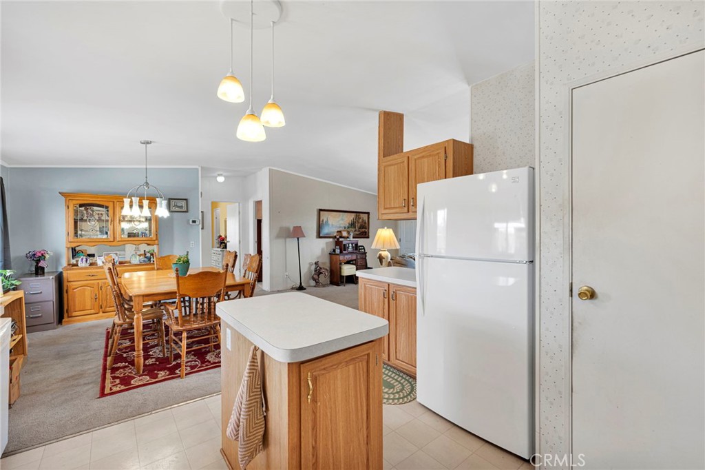 12837 Hacienda Road Phelan, CA 92371 - Photo 12 of 51 a kitchen view with a refrigerator a stove a dining table and chairs with wooden floor