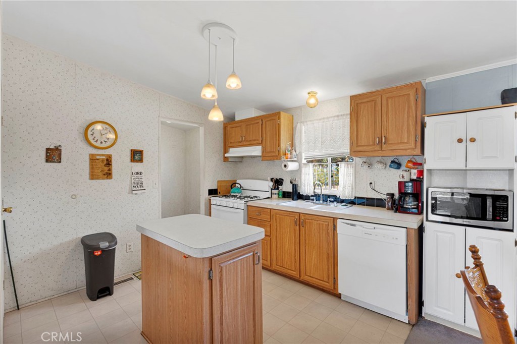 12837 Hacienda Road Phelan, CA 92371 - Photo 14 of 51 a kitchen with stainless steel appliances a refrigerator a stove a sink and white cabinets