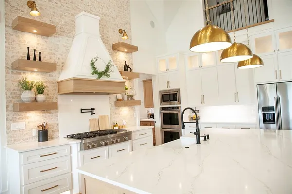 a kitchen with stainless steel appliances kitchen island granite countertop a sink a stove and a refrigerator