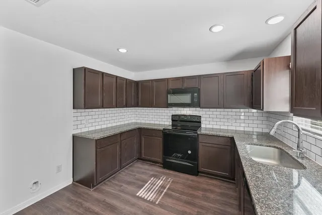 a kitchen with granite countertop a sink and a stove top oven