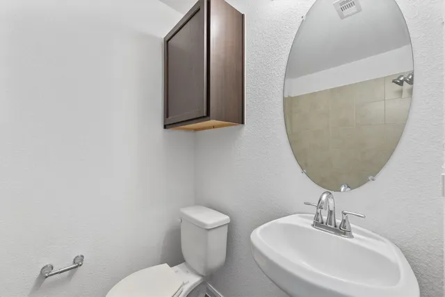 a bathroom with a toilet a sink and mirror