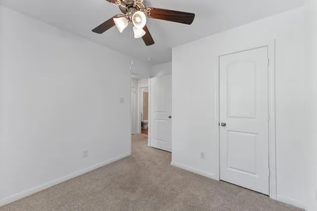 an empty room with closet and a chandelier fan
