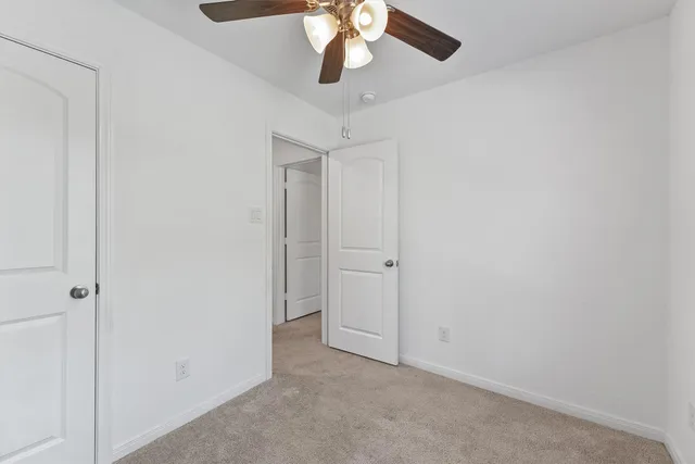 a view of an empty room and chandelier fan