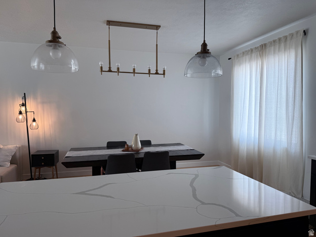 774 West 480 South American Fork, UT 84003 - Photo 19 of 76 Spacious room featuring a large dining table with seating, two clear glass pendant lights, a linear chandelier, and a prominent window with sheer curtains