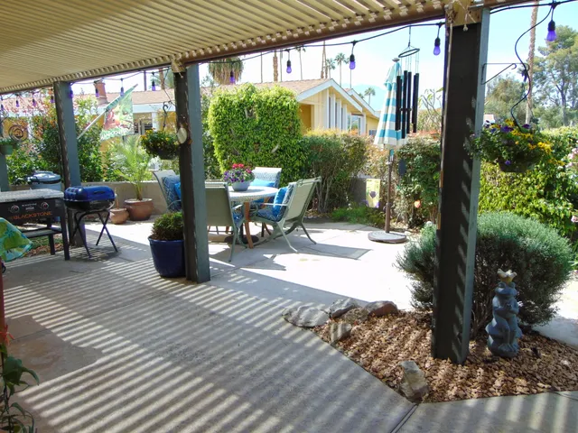 a view of a patio with table and chairs potted plants and floor to ceiling window