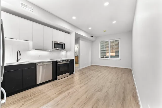 a kitchen with granite countertop a refrigerator and a stove top oven