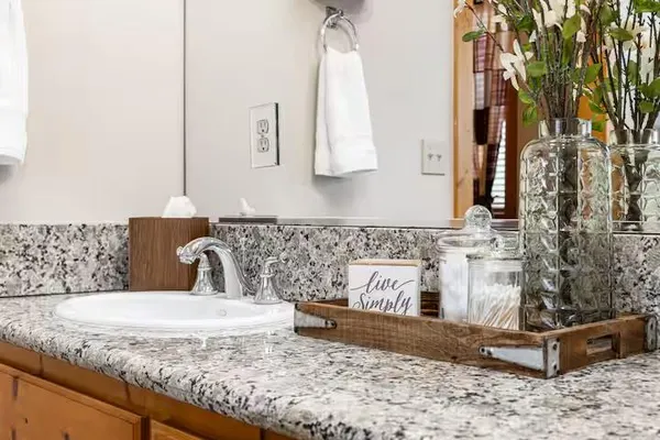 a bathroom with a granite countertop sink a mirror and a shower