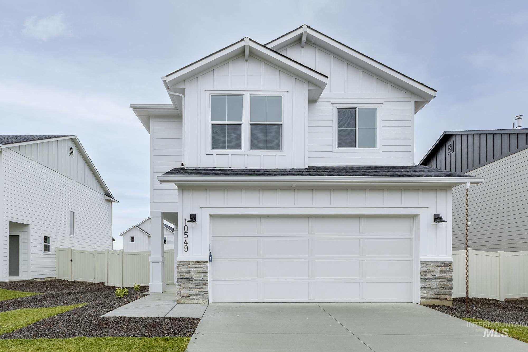View of front of home featuring board and batten siding, stone siding, a shingled roof, and concrete driveway
