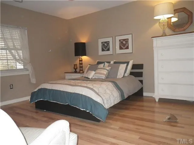 a bedroom with a bed lamp and wooden floor