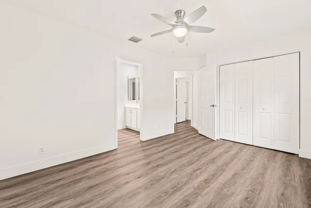 an empty room with wooden floor ceiling fan
