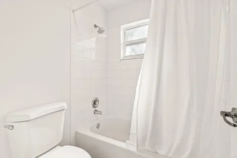 a white toilet sitting next to a bath tub