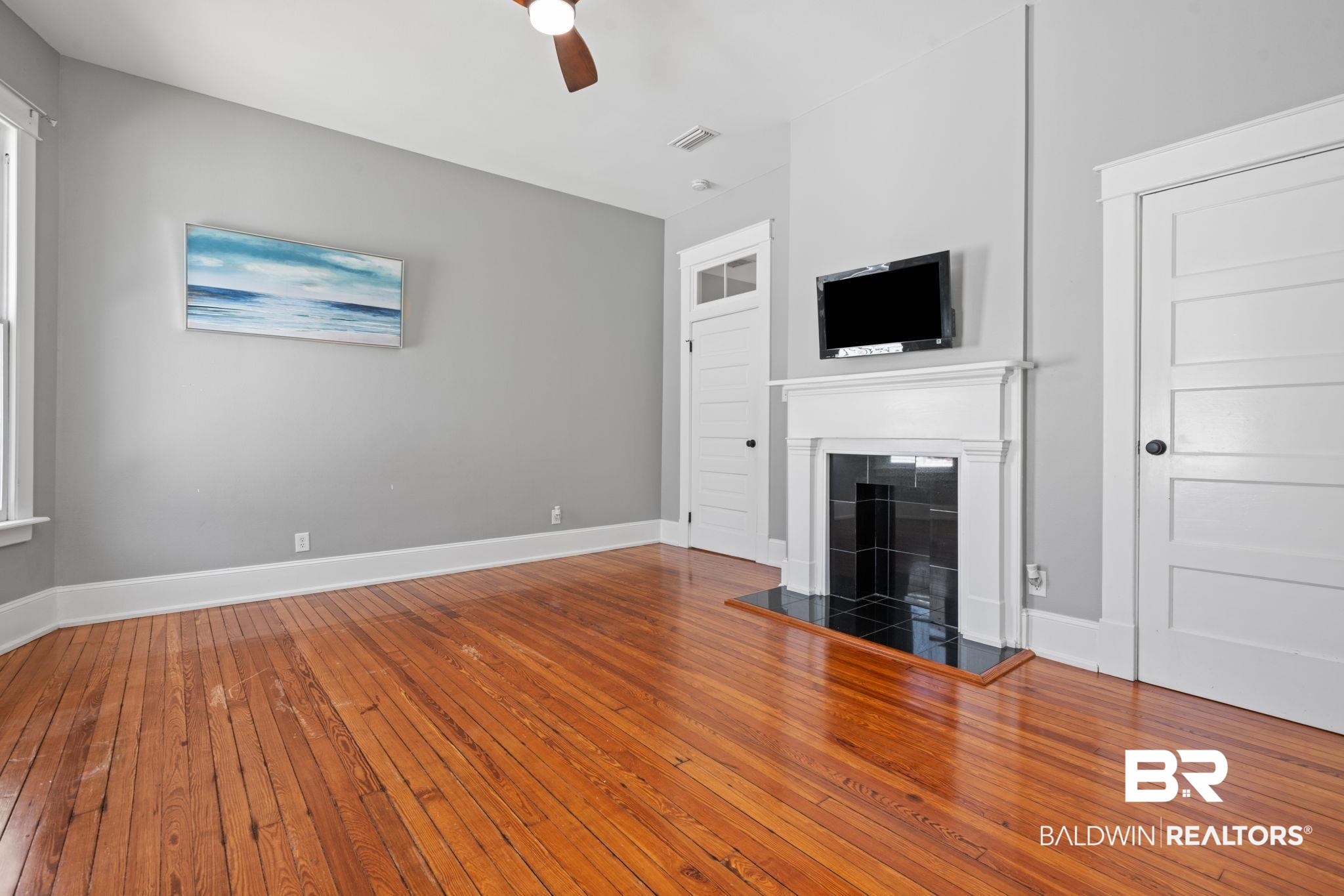 10 South Monterey Street Mobile, AL 36604 - Photo 22 of 45 Unfurnished living room featuring wood-type flooring, a fireplace, and a ceiling fan
