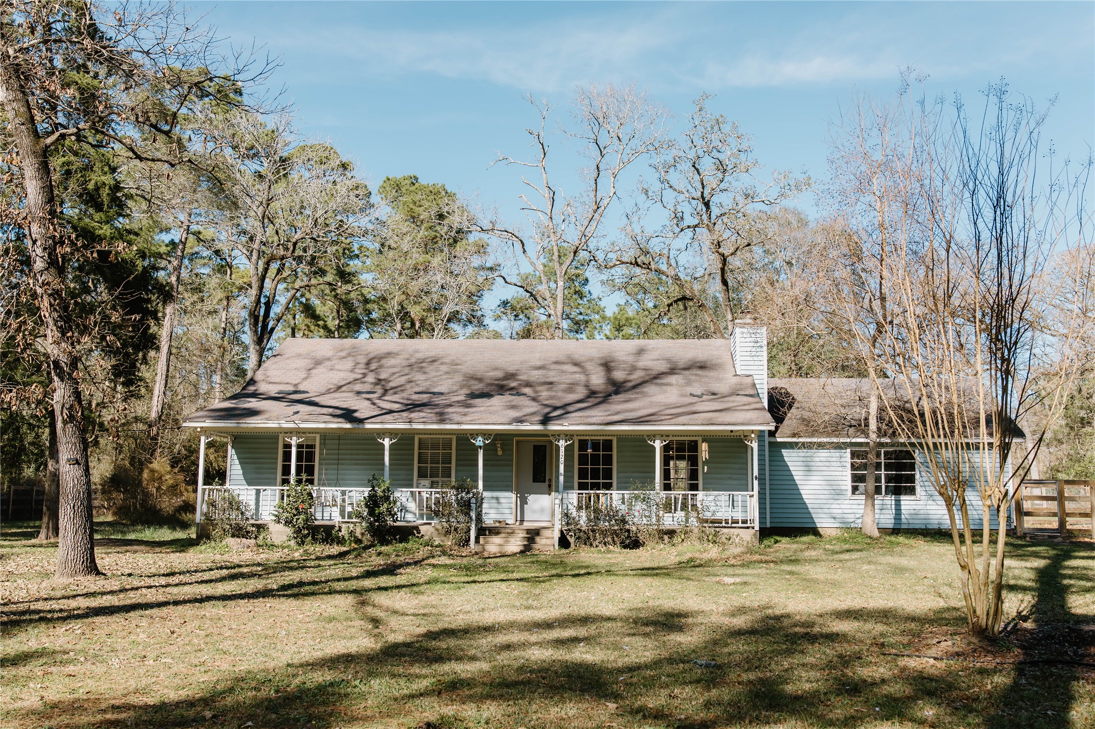 a front view of a house with swimming pool outdoor seating and covered with trees