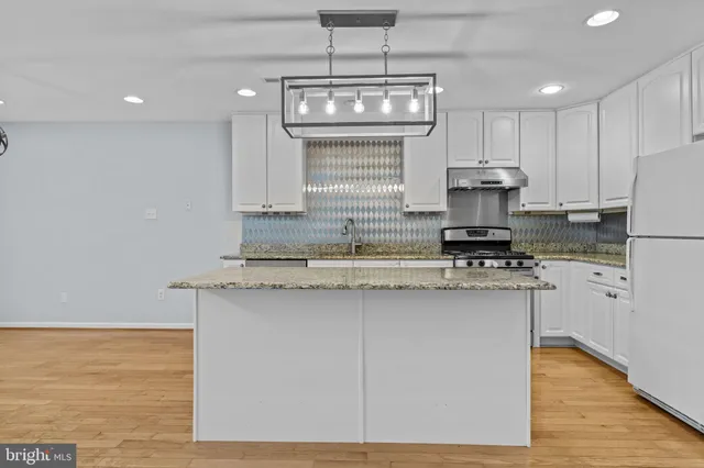 a kitchen with kitchen island granite countertop a sink cabinets and stainless steel appliances