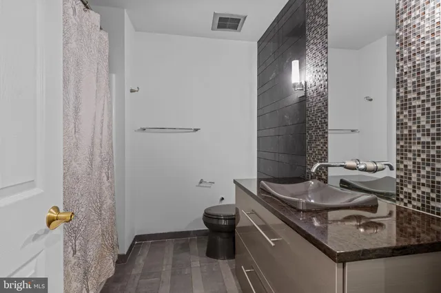 a bathroom with a granite countertop sink a toilet and shower