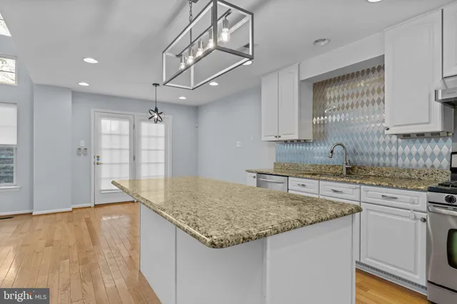 a kitchen with granite countertop a sink a counter space appliances and cabinets