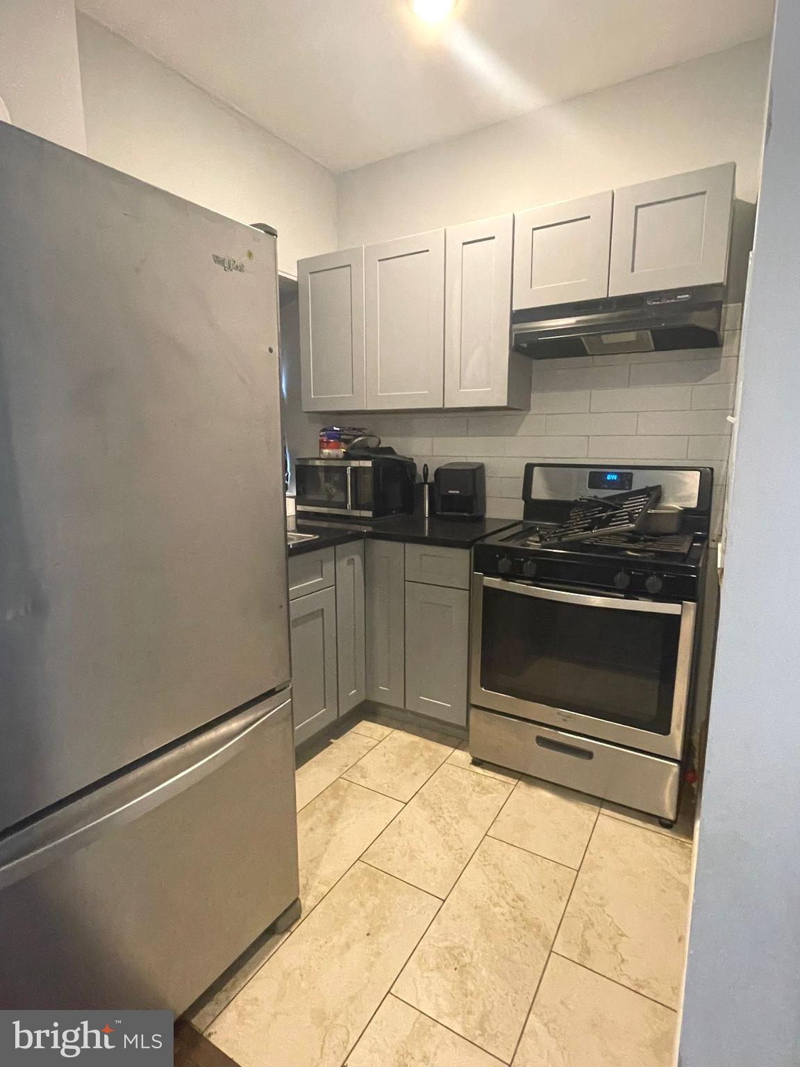 5322 Wayne Avenue Philadelphia, PA 19144 - Photo 6 of 21 a kitchen with granite countertop a stove a microwave and a refrigerator