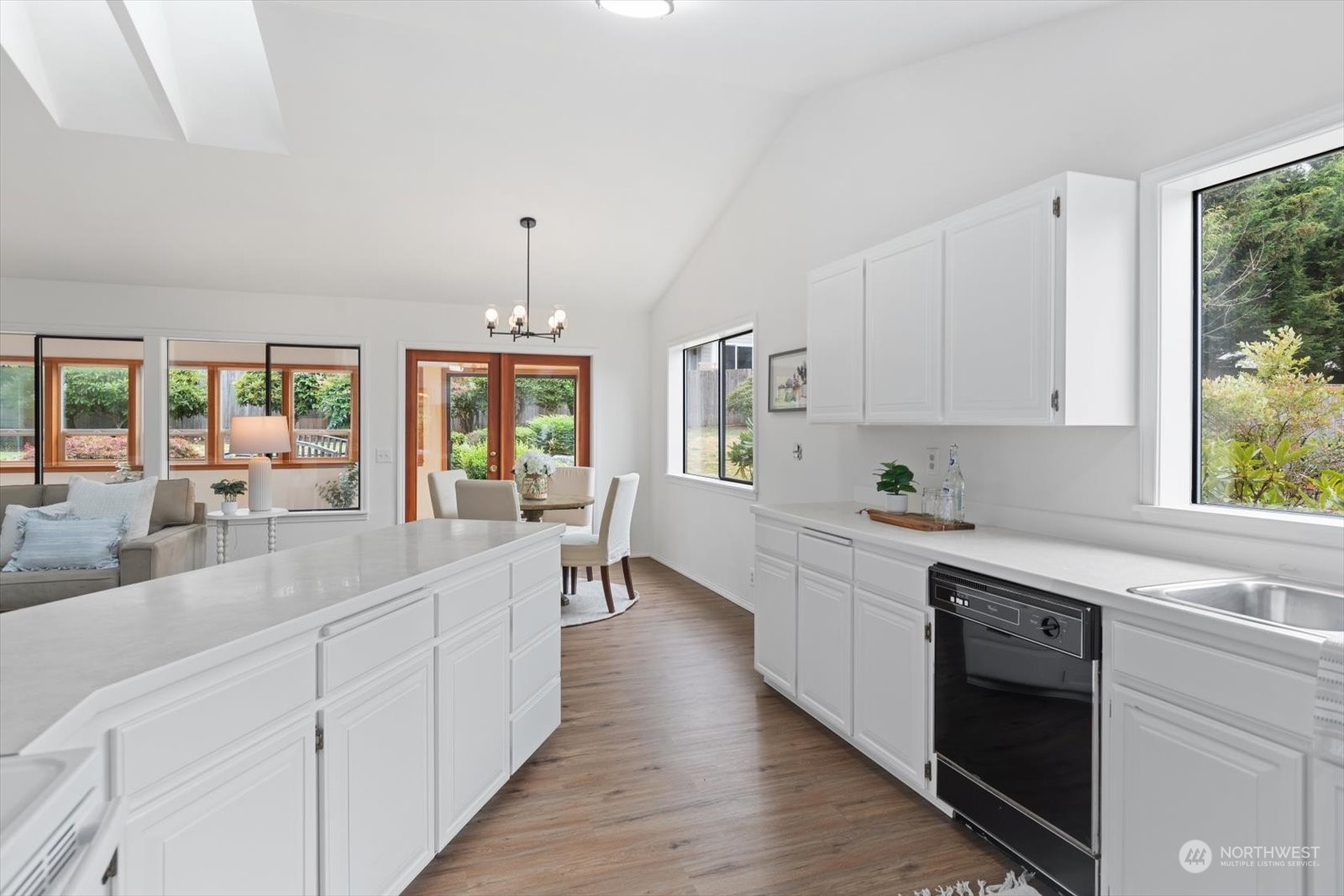 2480 215th Place Southwest Brier, WA 98036 - Photo 22 of 40 a large white kitchen with granite countertop a stove top oven a sink dishwasher and white cabinets with wooden floor