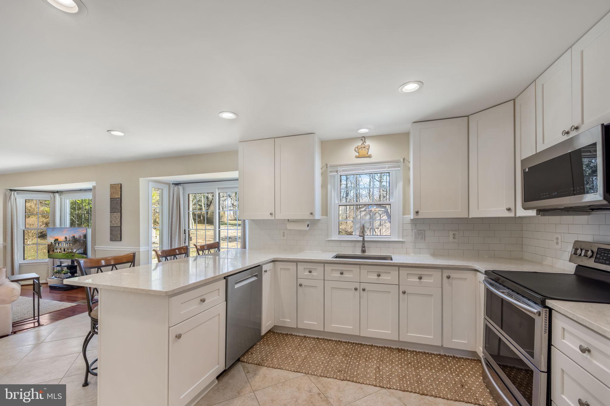 8504 Silverdale Road Lorton, VA 22079 - Photo 11 of 48 a large white kitchen with stainless steel appliances granite countertop a sink and cabinets