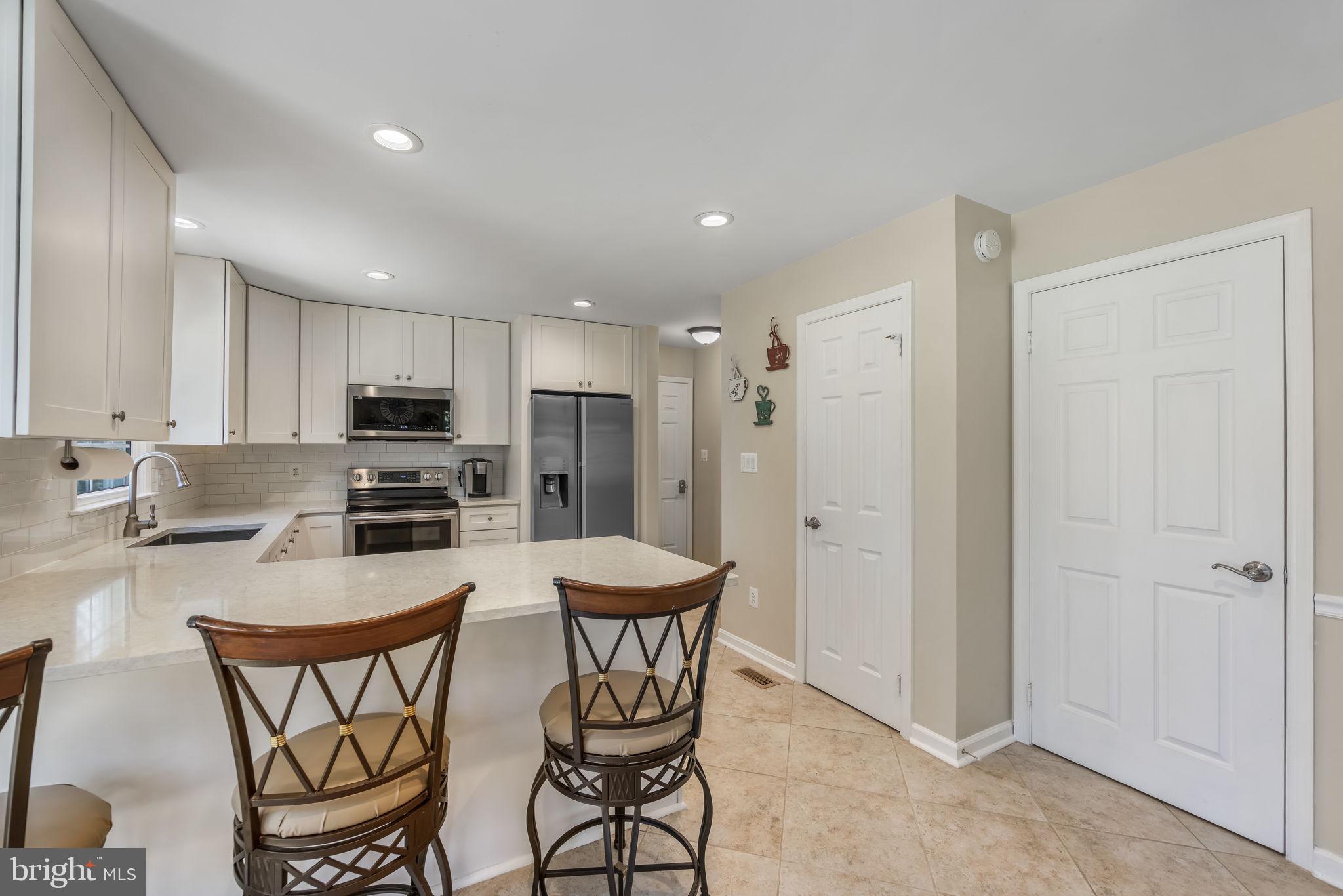 8504 Silverdale Road Lorton, VA 22079 - Photo 14 of 48 a kitchen with stainless steel appliances a dining table chairs refrigerator and microwave
