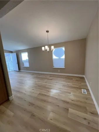 an empty room with wooden floor and kitchen view