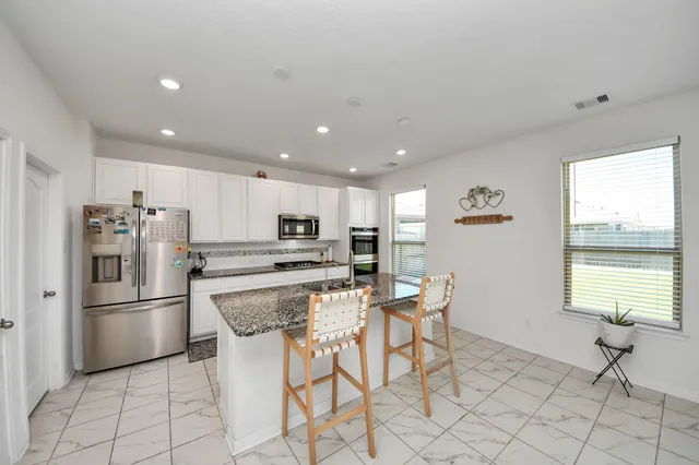 a kitchen with stainless steel appliances kitchen island granite countertop a refrigerator and a stove top oven
