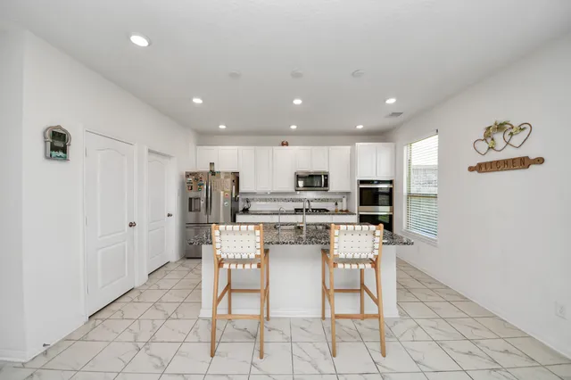 a kitchen with stainless steel appliances kitchen island granite countertop a refrigerator and a stove top oven