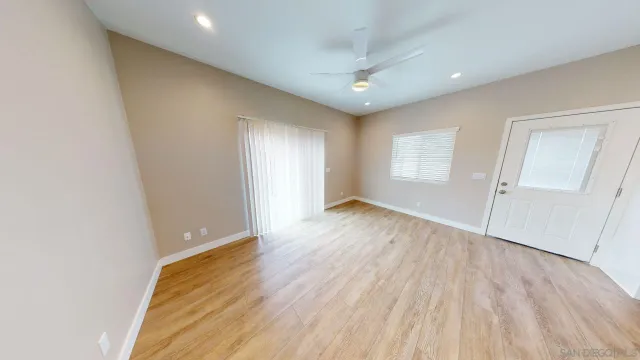 an empty room with wooden floor cabinet and windows