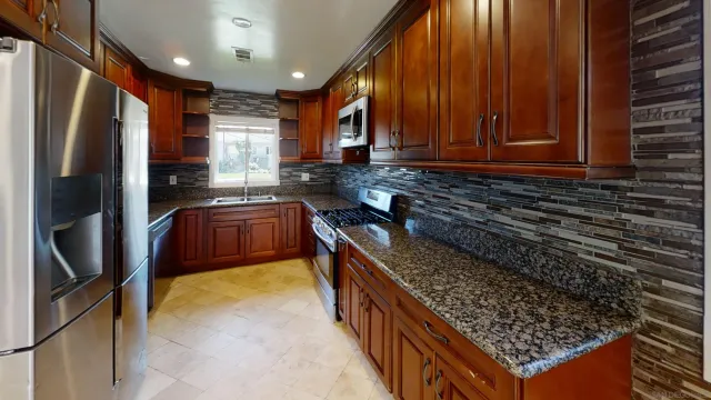 a kitchen with stainless steel appliances granite countertop a refrigerator a sink and wooden cabinets