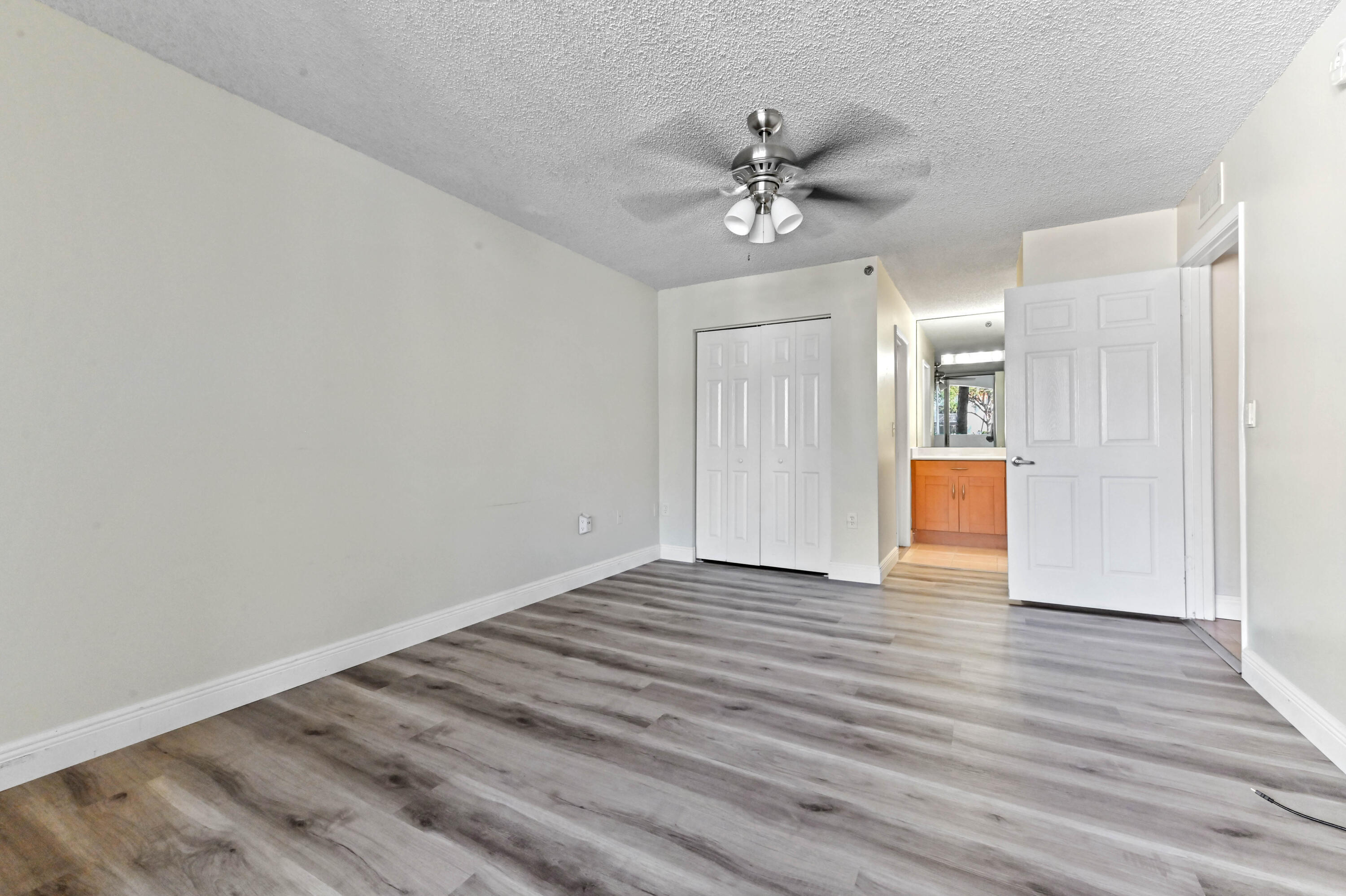 3237 Clint Moore Road, Unit 107 Boca Raton, FL 33496 - Photo 19 of 41 a view of an empty room with wooden floor and fan