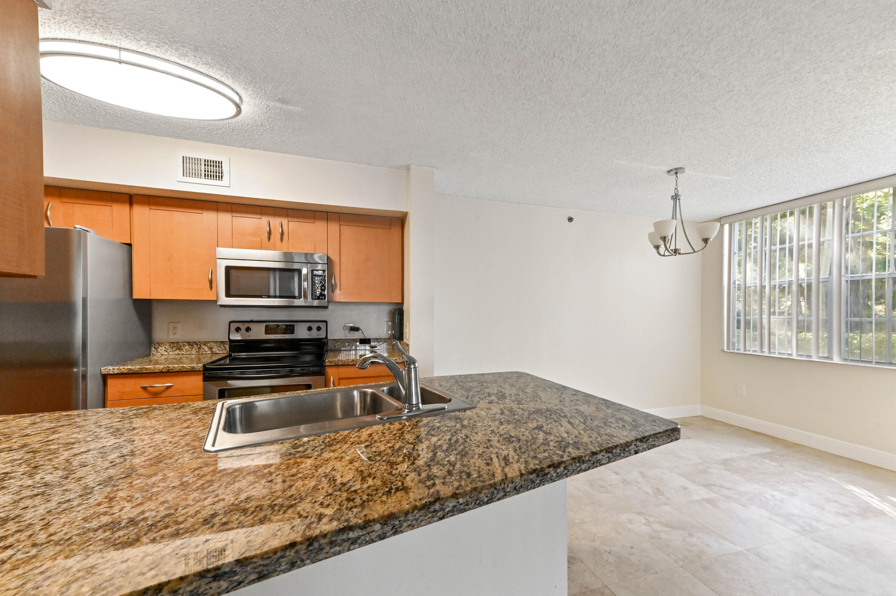 3237 Clint Moore Road, Unit 107 Boca Raton, FL 33496 - Photo 7 of 41 a kitchen with stainless steel appliances granite countertop a sink stove and refrigerator