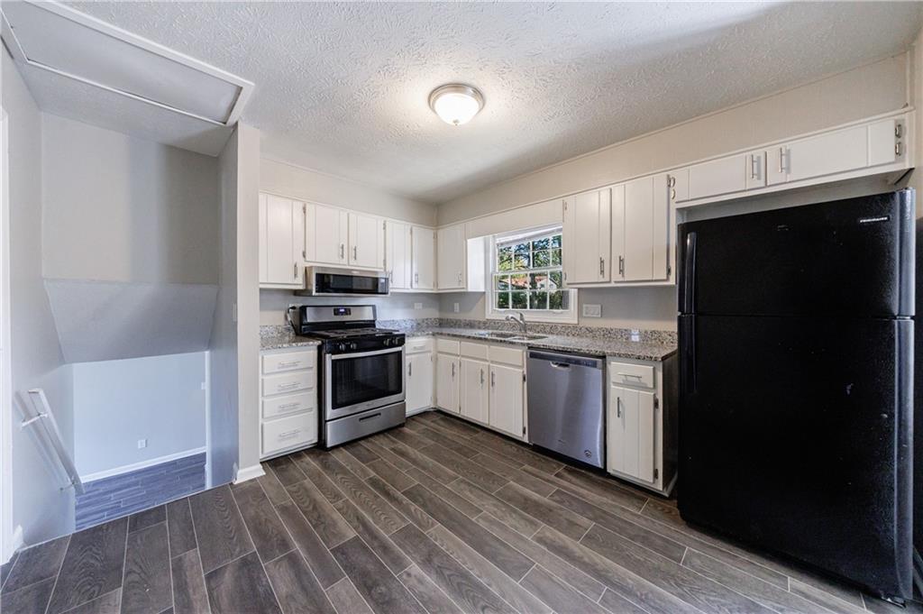 5755 Bearing Way Atlanta, GA 30349 - Photo 10 of 31 a kitchen with granite countertop a refrigerator stove and microwave