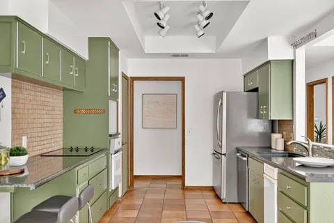 a kitchen with stainless steel appliances granite countertop a sink and a refrigerator