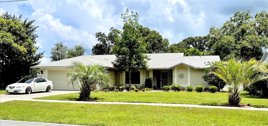 2403 Landover Boulevard Spring Hill, FL 34608 - Photo 1 of 1 a front view of a house with a garden and trees