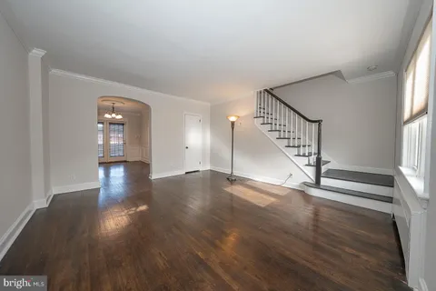 a view of an empty room with wooden floor and stairs
