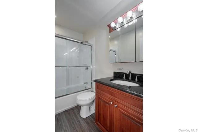 a bathroom with a granite countertop sink a toilet a mirror and shower