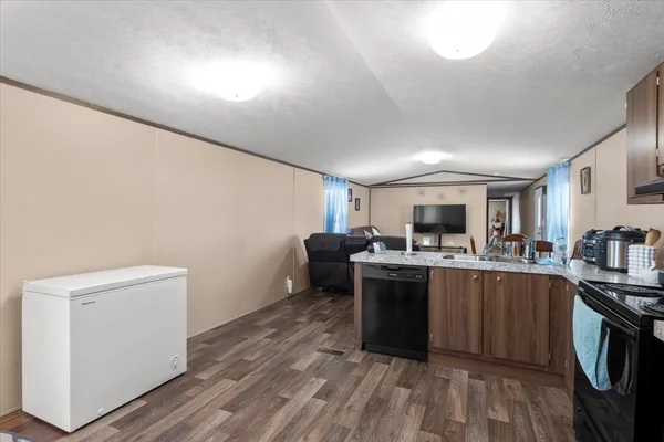 a kitchen with stainless steel appliances kitchen island granite countertop a refrigerator a stove a sink dishwasher and a refrigerator with wooden cabinets