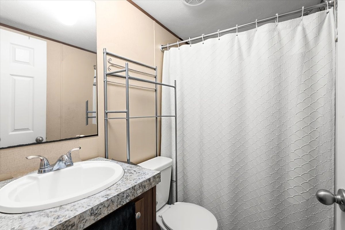 341 Southwest Front Street Bartlett, TX 76511 - Photo 13 of 23 a bathroom with a granite countertop sink toilet and a mirror