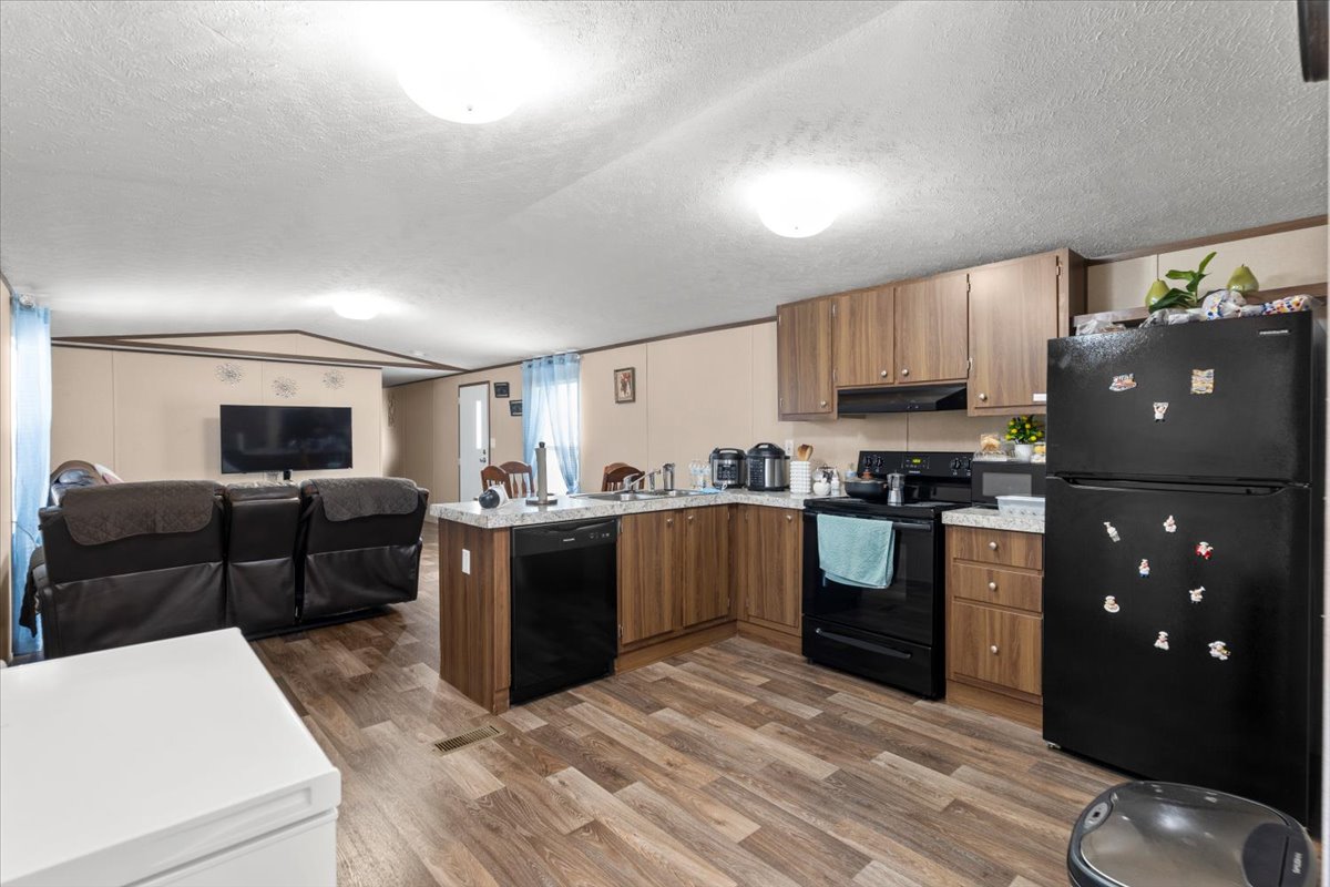 341 Southwest Front Street Bartlett, TX 76511 - Photo 21 of 23 a kitchen with stainless steel appliances kitchen island granite countertop a refrigerator a stove a sink dishwasher and a refrigerator with wooden cabinets