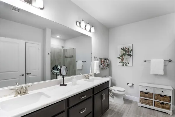 a bathroom with a double vanity sink a toilet and a mirror