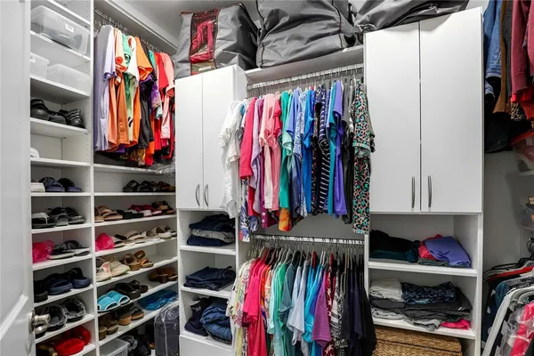 a view of walk in closet with clothes and shoes