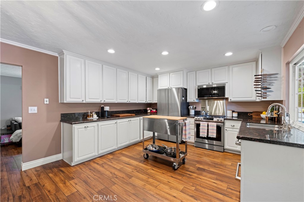 23255 Redbud Ridge Circle Valencia, CA 91354 - Photo 11 of 19 a kitchen with granite countertop a stove top oven a sink dishwasher a dining table and chairs with wooden floor