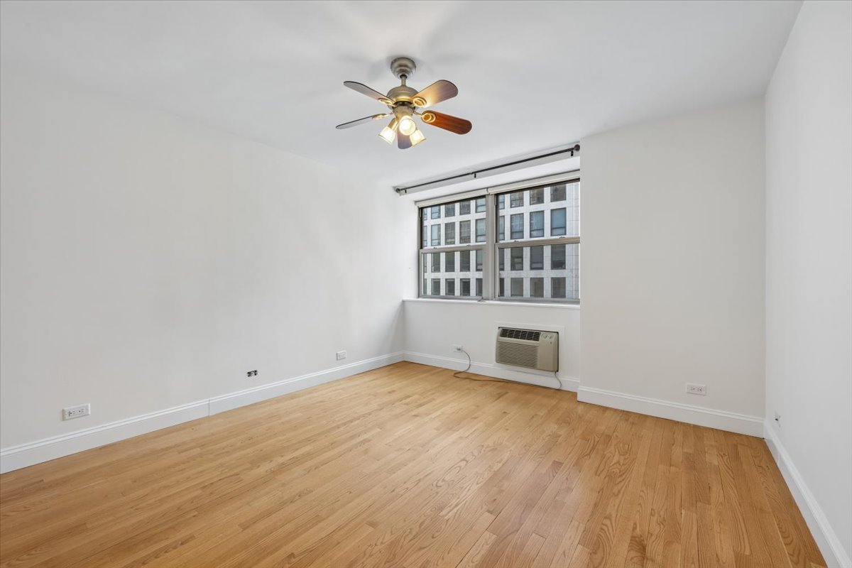 253 East Delaware Place, Unit 11F Chicago, IL 60611 - Photo 6 of 19 a view of an empty room with a window and wooden floor