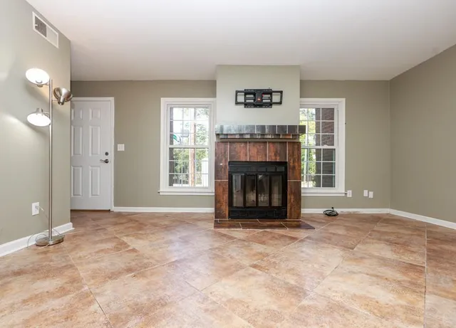 a view of an empty room with wooden floor and fireplace