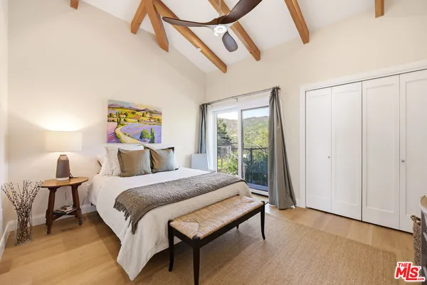 a bedroom with a bed a dresser and potted plants on the table