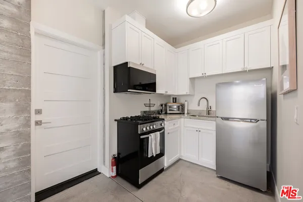 a kitchen with a refrigerator stove and white cabinets