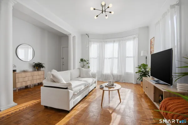 a living room with furniture a flat screen tv and a large window