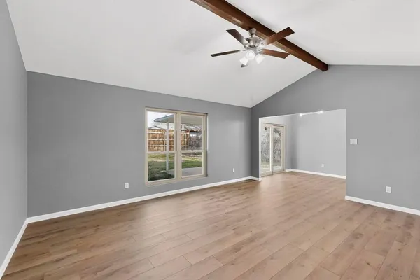 a view of an empty room with wooden floor and a window