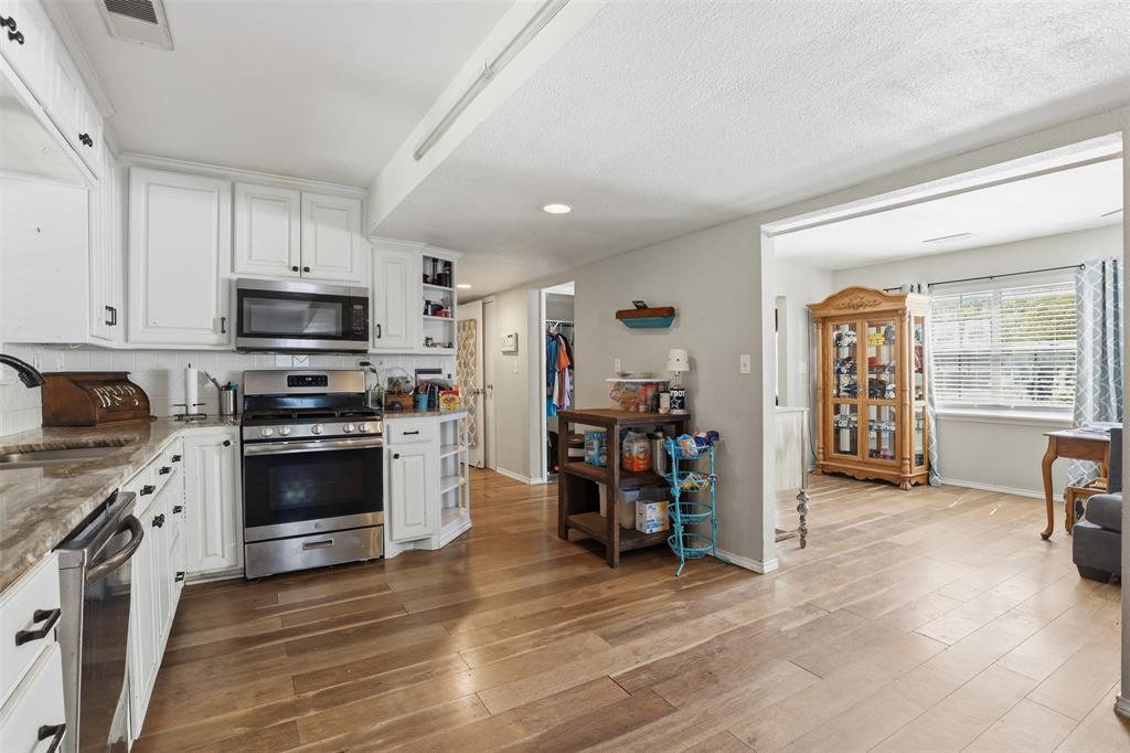 500 West Rucker Street Granbury, TX 76048 - Photo 12 of 35 a kitchen with stainless steel appliances kitchen island wooden cabinets and a stove top oven