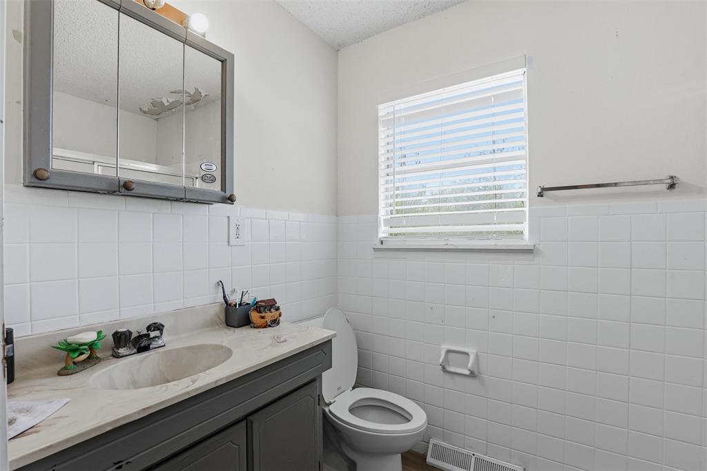500 West Rucker Street Granbury, TX 76048 - Photo 24 of 35 a bathroom with a granite countertop sink mirror and toilet